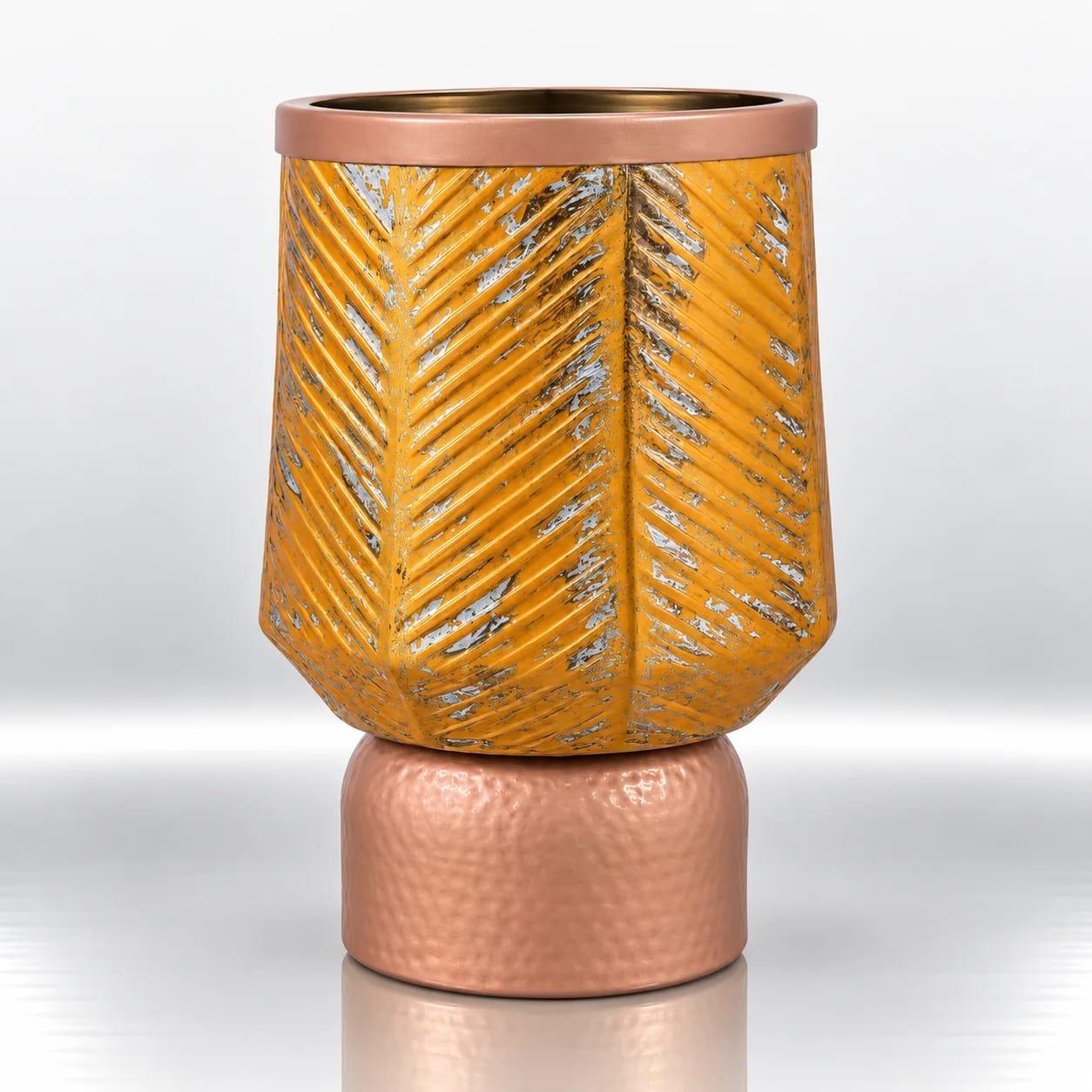Amber gold glass candle holder with raised chevron detailing, distressed metallic accents and a textured rose-gold base.