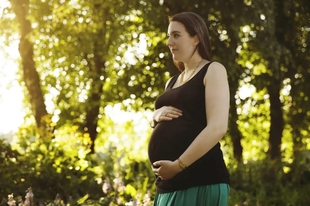 Pregnant woman in a green skirt enjoying a serene moment in Maxwell Park during a maternity session in Rutherglen.