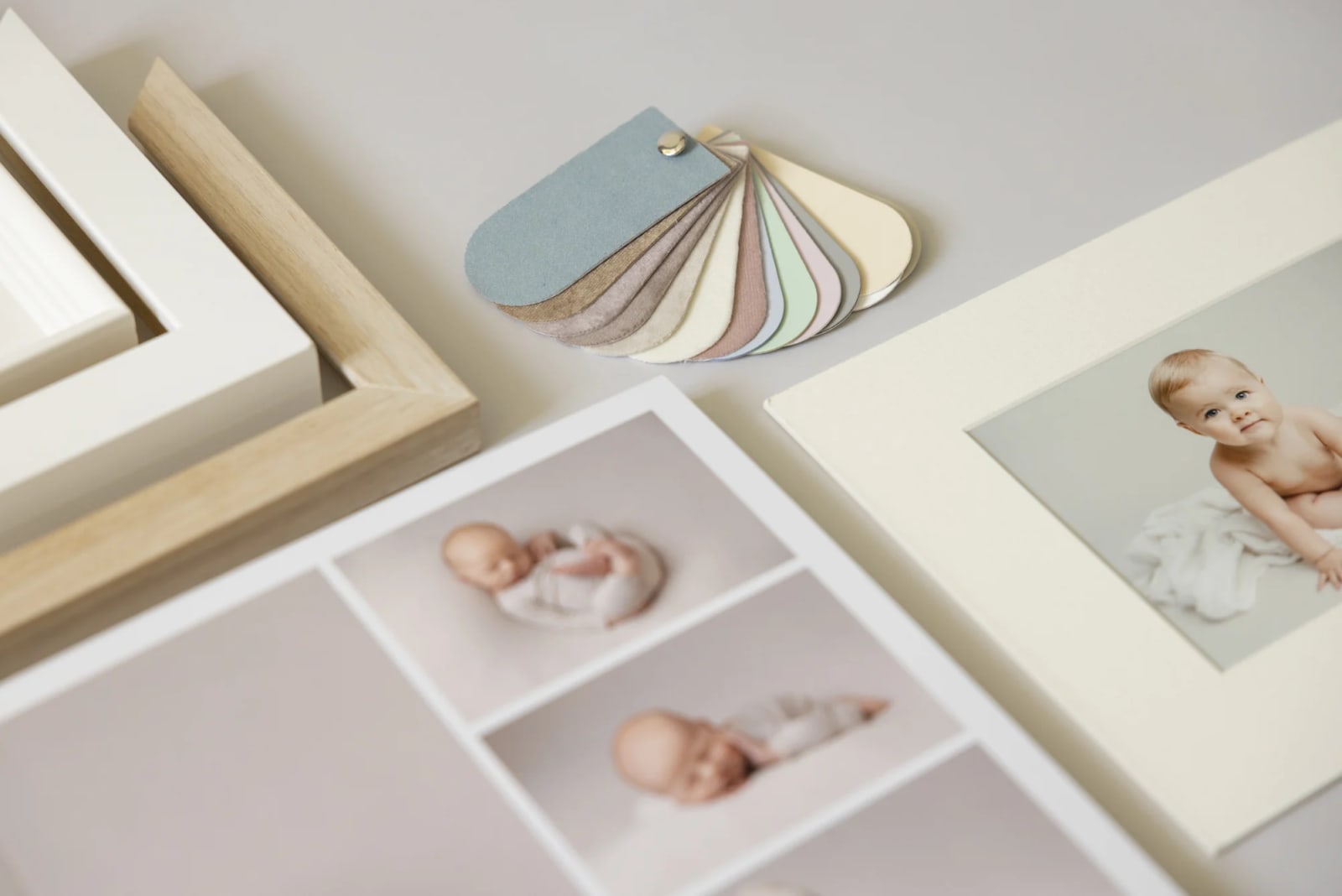 A selection of framed baby photos and pastel color swatches showcasing Louise Mallan Photography in Newton.