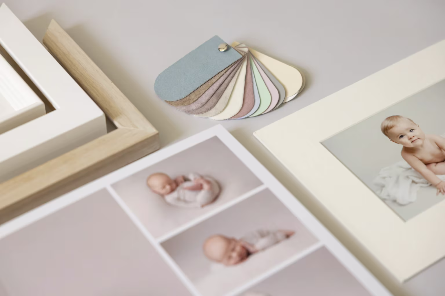 A selection of framed baby photos and pastel color swatches showcasing Louise Mallan Photography in Newton