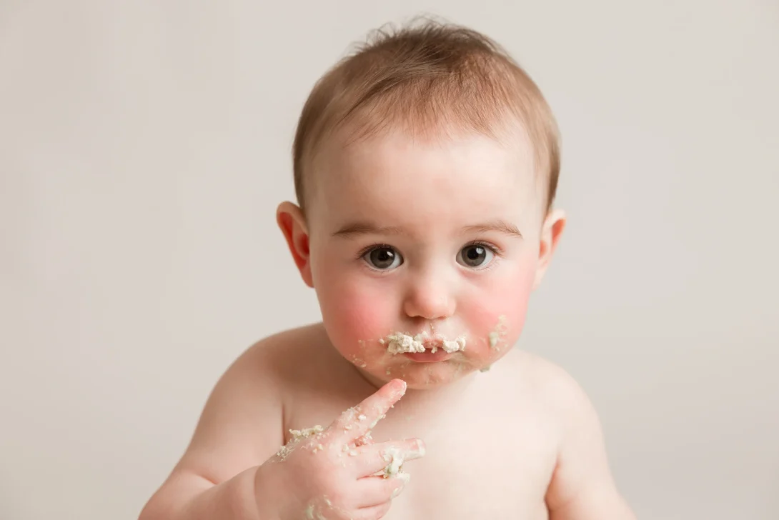 Adorable baby enjoying a cake smash session with cake on their face during a photoshoot in Cambuslang