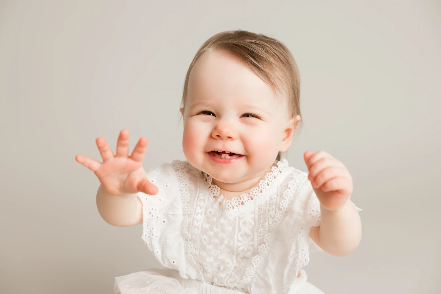 Smiling baby reaching out, captured in a charming baby photography session in Cambuslang studio.