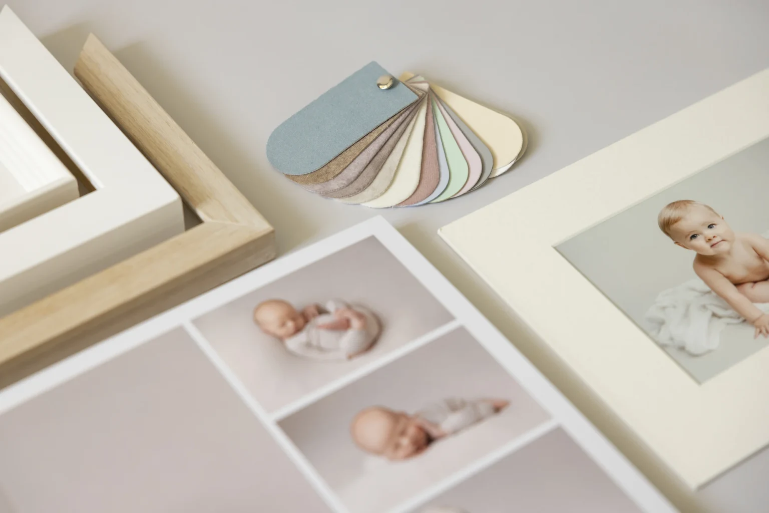 A selection of framed baby photos and pastel color swatches showcasing Louise Mallan Photography in Newton
