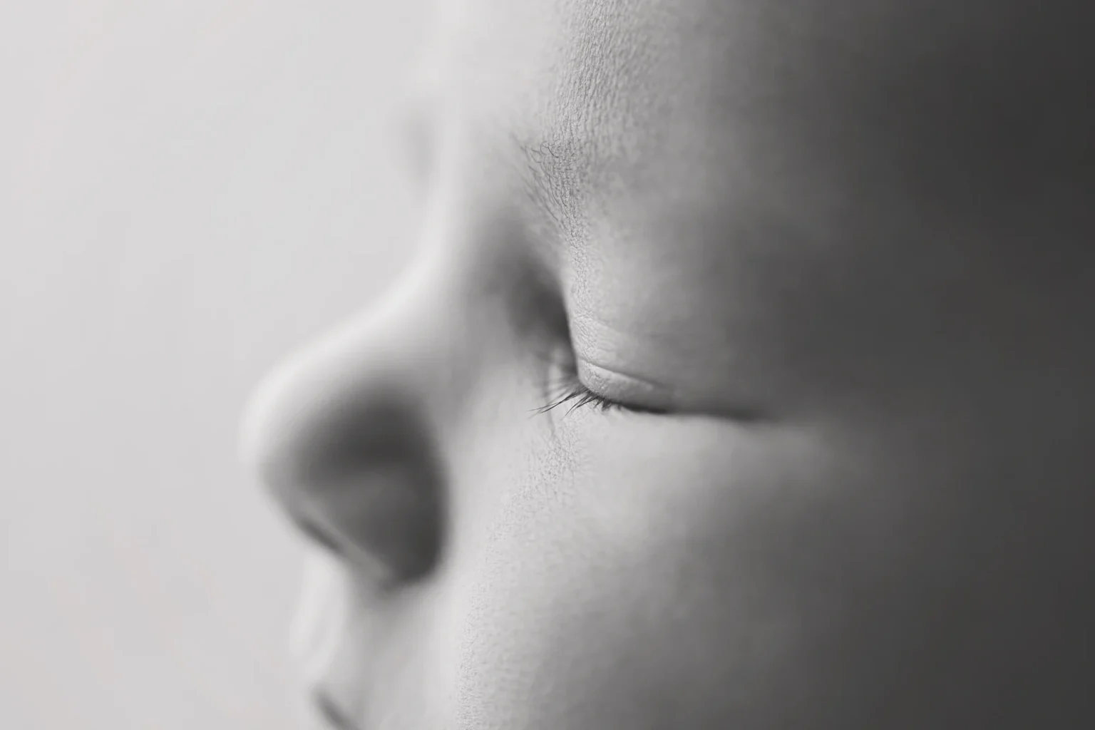 Close-up of a newborn's peaceful face highlighting delicate features captured in black and white photography