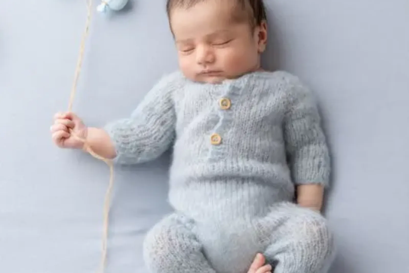 Two young siblings gently holding a swaddled newborn on a cozy blanket, capturing a tender moment in newborn photography