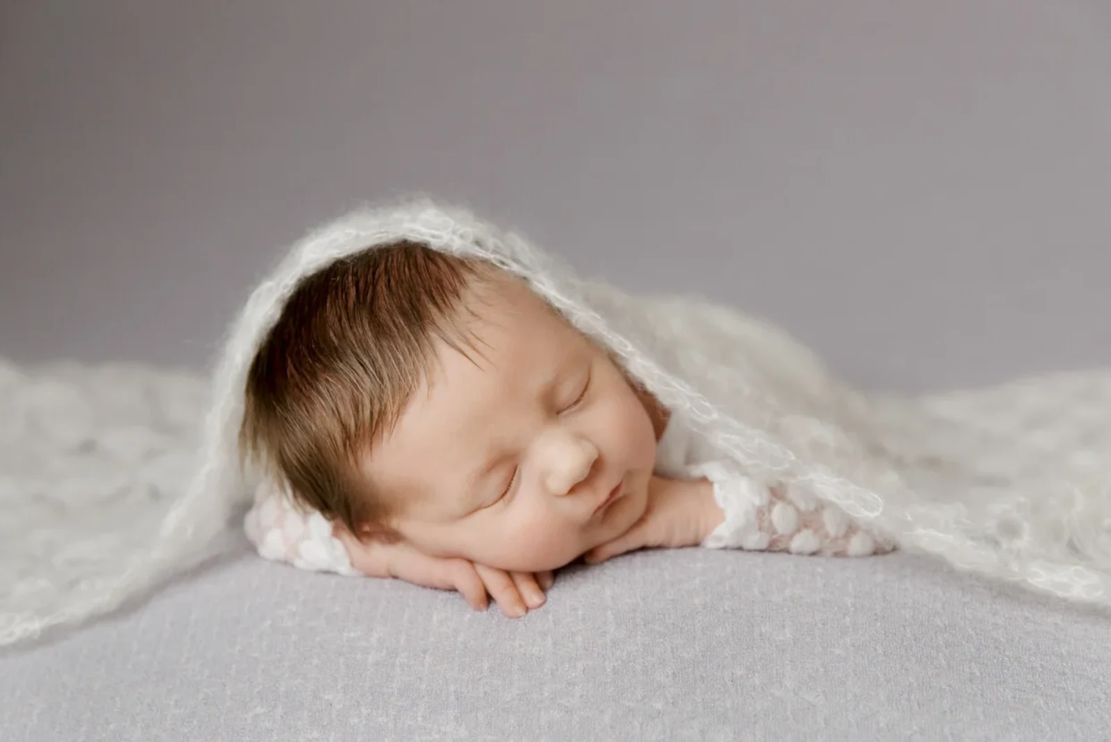 Peaceful newborn baby sleeping under a soft white blanket, captured in East Kilbride