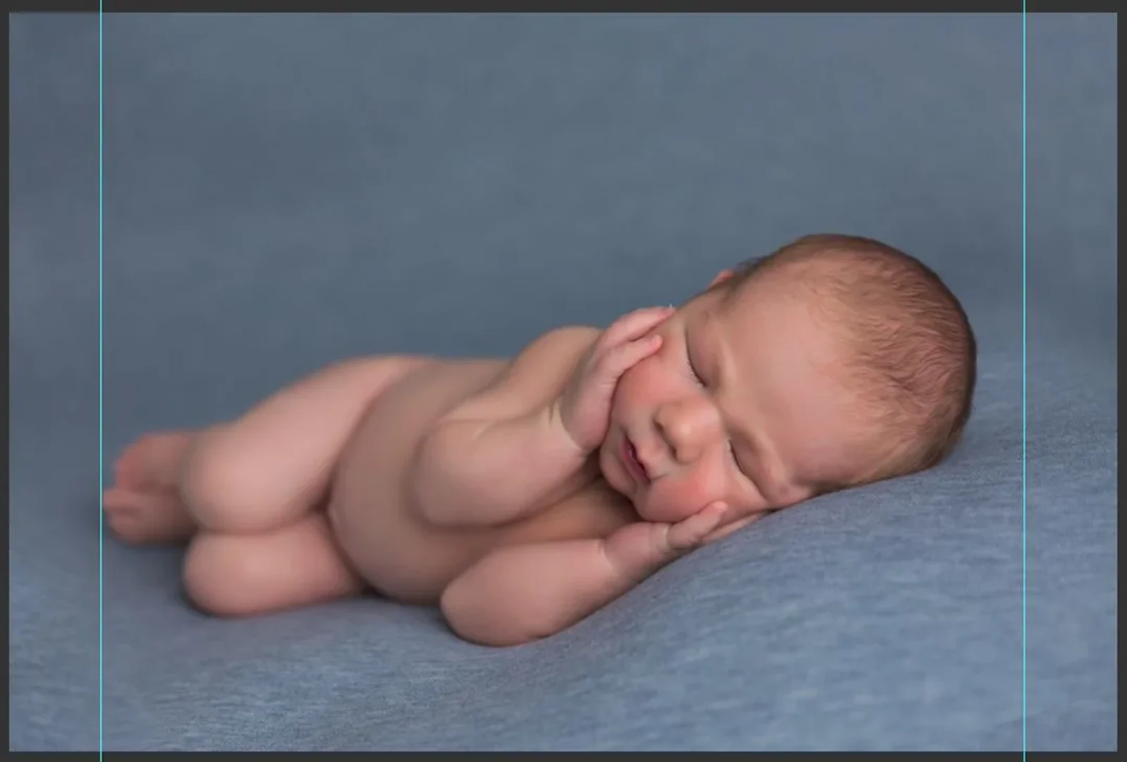 Newborn baby posed on a blue blanket, showcasing ideal cropping techniques in photography
