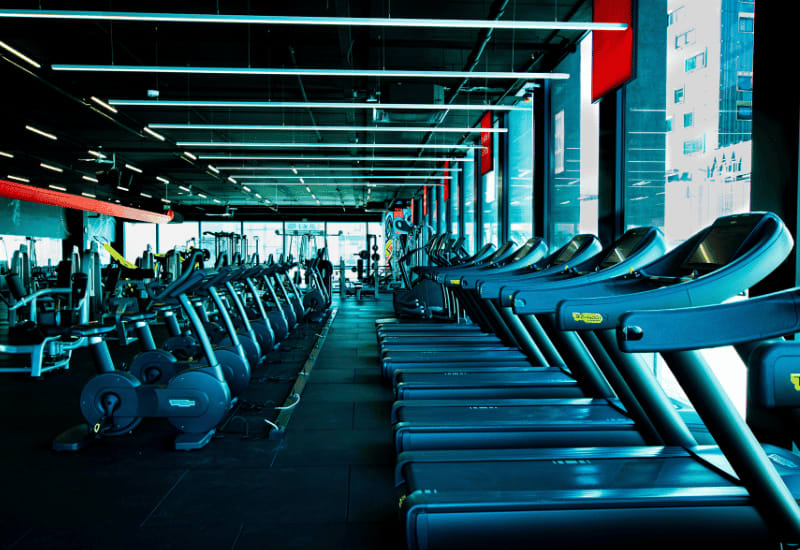 Rows of treadmills and exercise bikes inside a modern gym