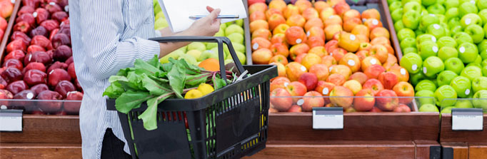 Woman holding basket shopping for fruits and vegetables.