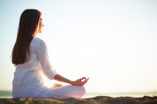 Woman mediating on the beach