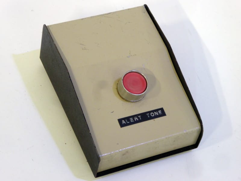 Single red button on brown & beige sloping desktop box. Mute alarm, PTT etc