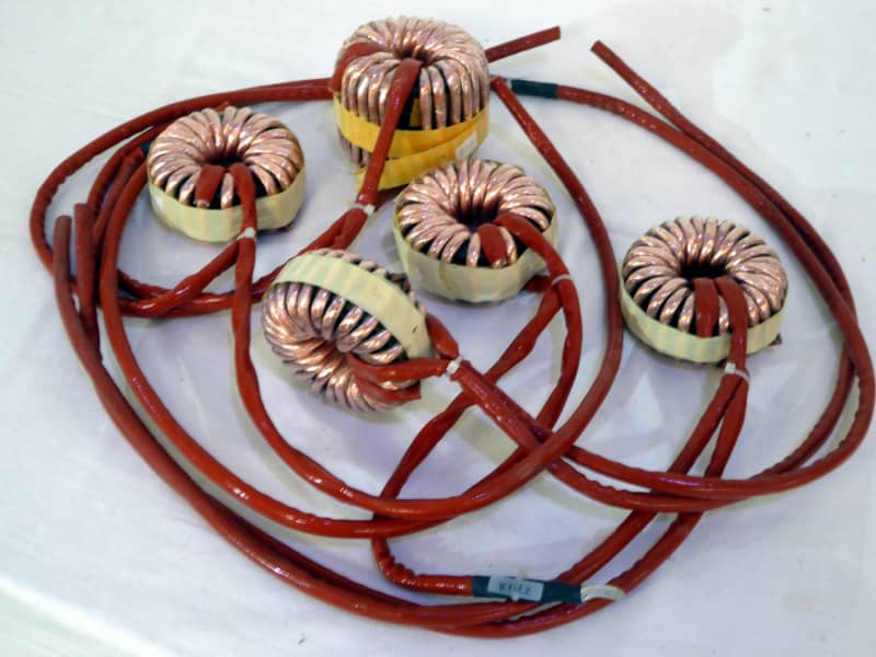 Copper doughnut shaped toroidal coils with long blood red wires