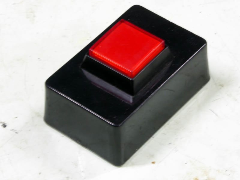 Small red desktop push button/switch on black base