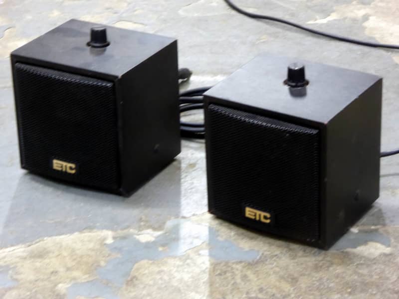 Small cube shaped black desktop speakers with volume control on top