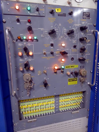 Tall practical battleship grey military control panel with winking coloured lamps, switches