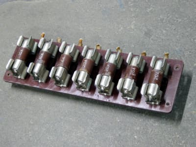 Row of large brown cartridge fuses on brown base board