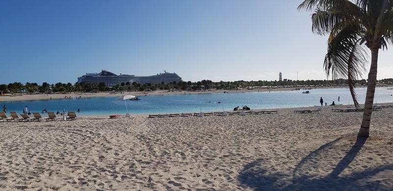Turquoise lagoon and white-sand beach at Ocean Cay in the Bahamas, with an MSC ship offshore