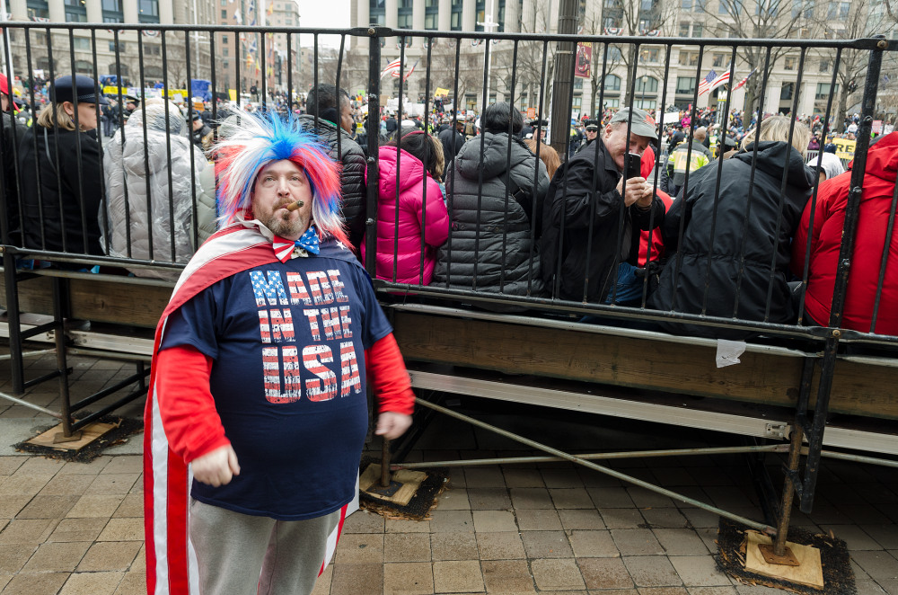 A man in a patriotic outfit stands in front of a crowd at a rally