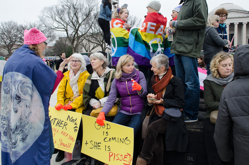 A diverse group of protesters holding signs and wearing colorful attire at a rally