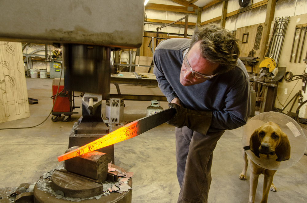 A blacksmith using a forge to shape a glowing hot piece of metal, with a dog watching nearby
