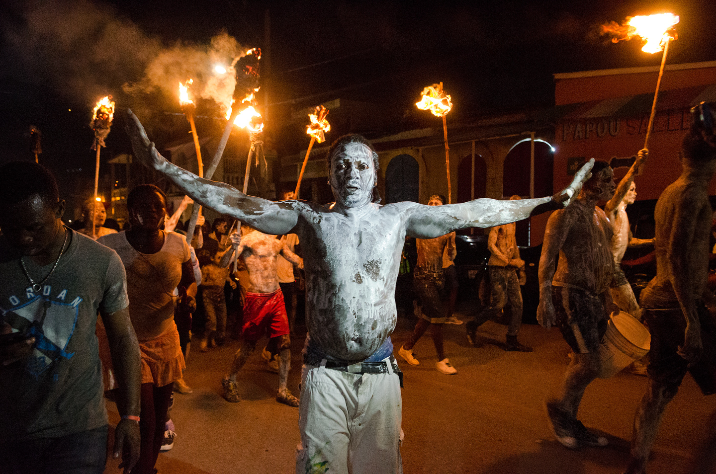 A group of people with painted bodies carrying torches during a nighttime festival