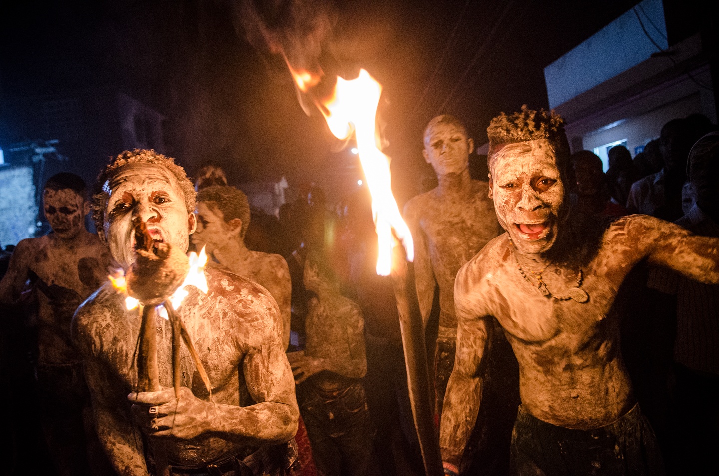Participants in a night festival wearing body paint and holding torches
