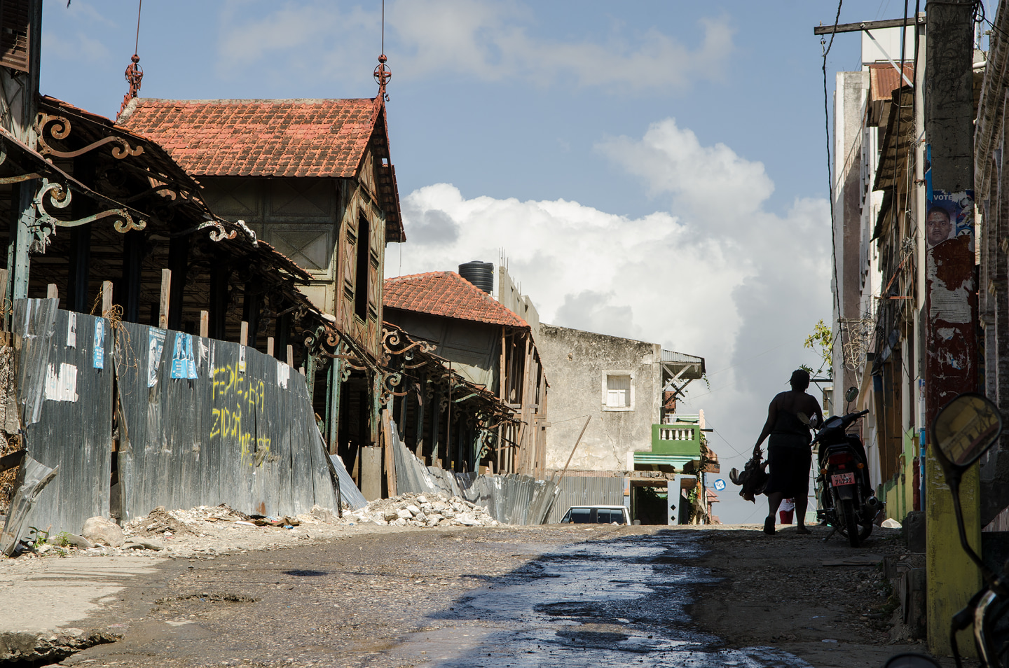 A narrow street lined with dilapidated buildings and a person walking away