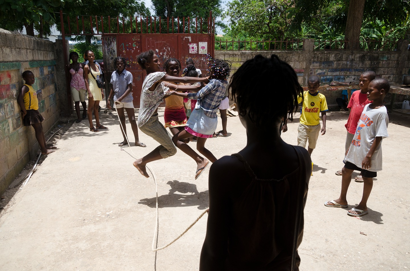 Children playing jump rope in a sunny outdoor space