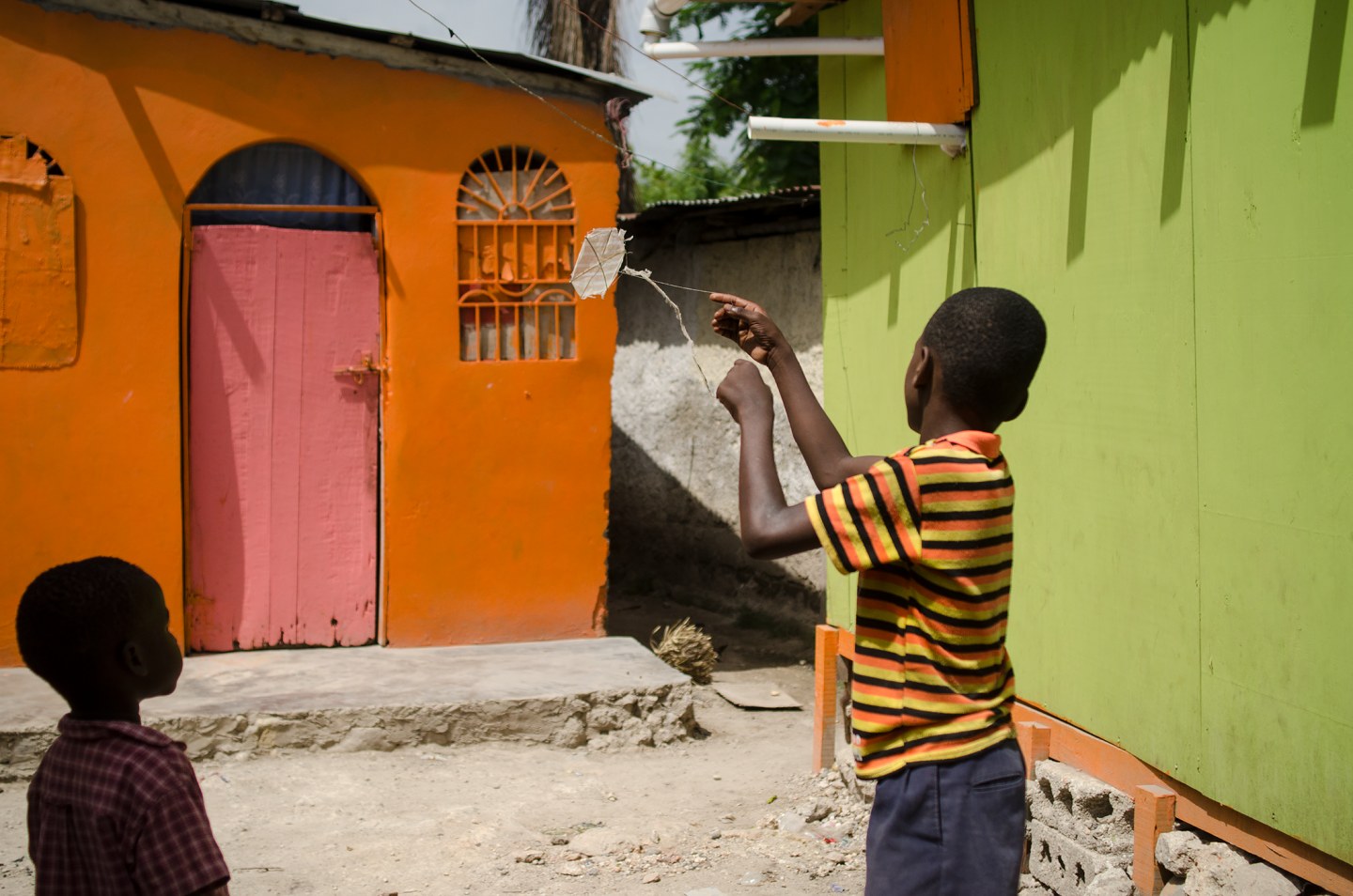 Two children play in a vibrant alleyway with colorful buildings