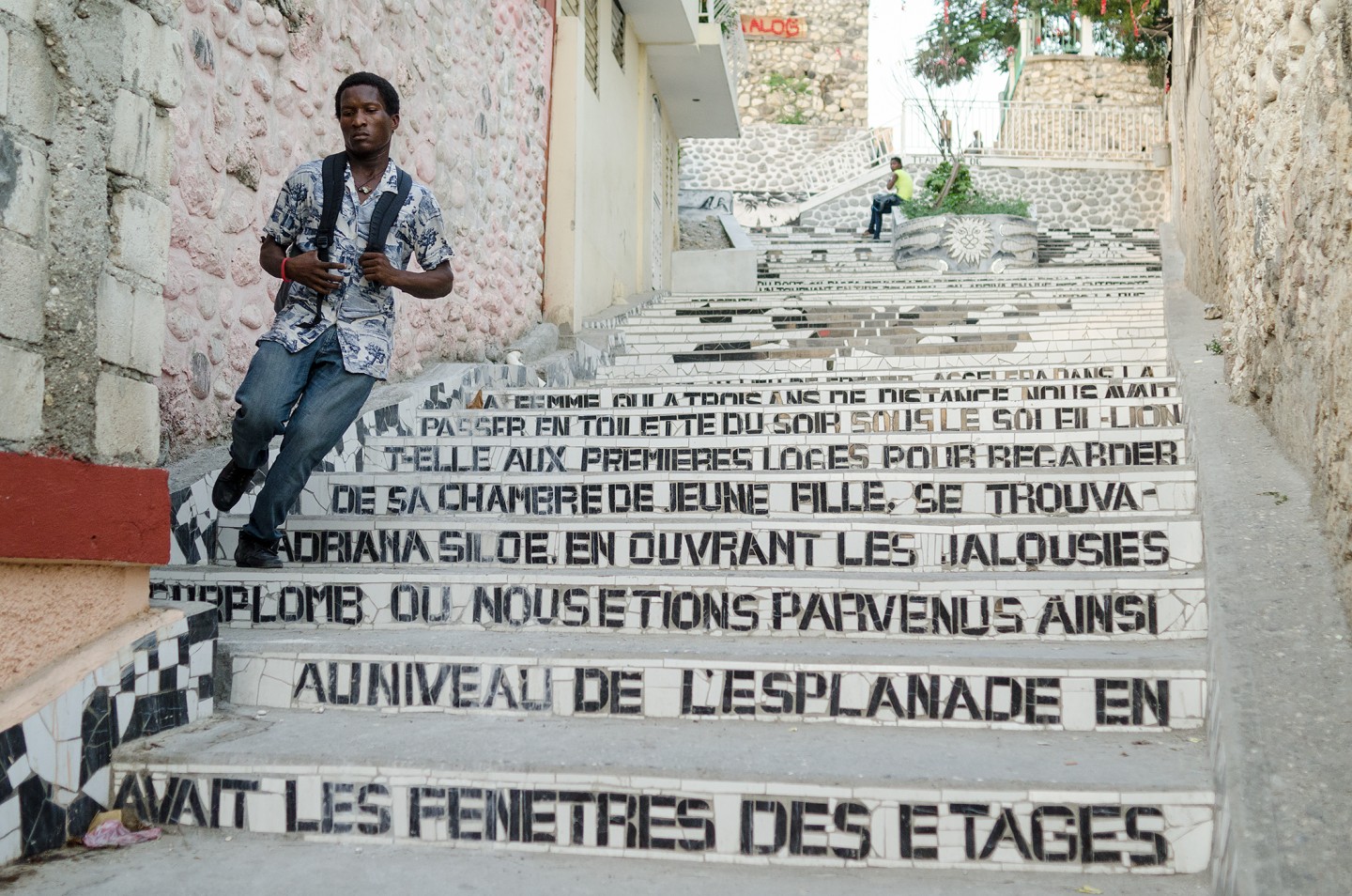 A person stands on colorful stairs adorned with various artistic texts