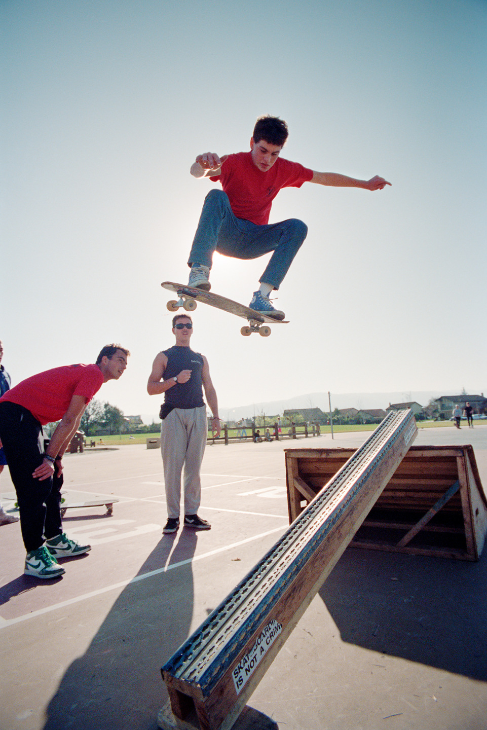 Skateboarder performing a jump over a ramp with spectators watching