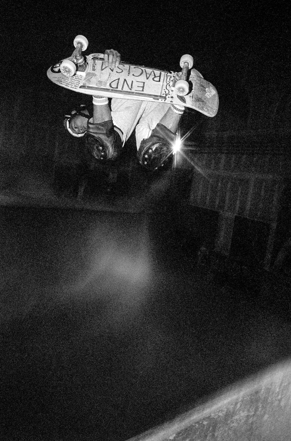 Skateboarder performing an aerial trick in a dimly lit skatepark