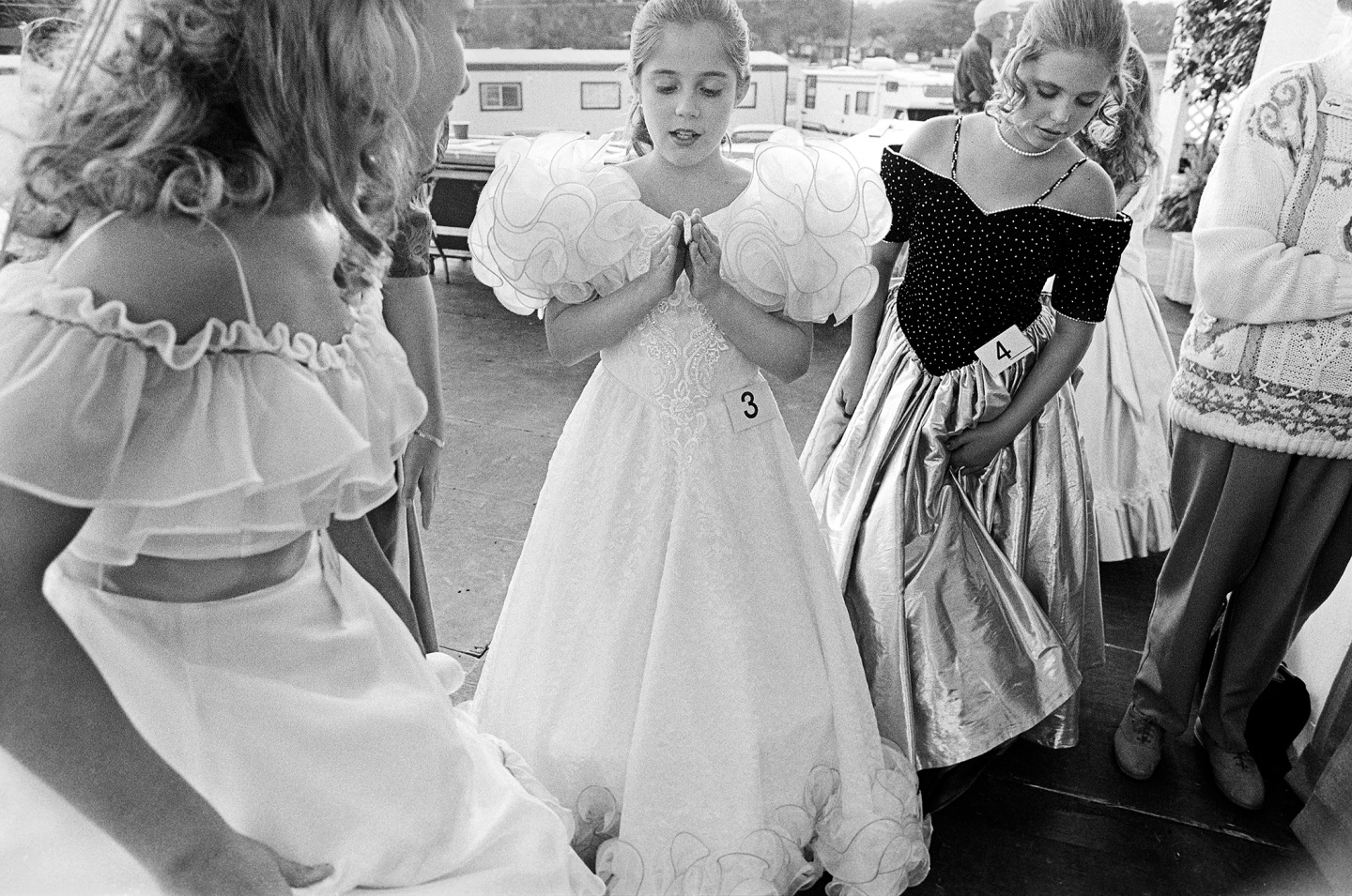 Three young girls in formal dresses preparing for an event