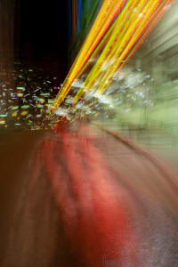 Abstract nighttime scene with streaks of colored light and reflections on a wet surface