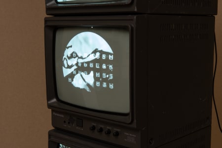 Stacked vintage televisions displaying a monochrome image of a mountainous landscape with a moon