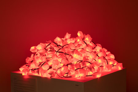 A pile of red glowing lights resembling crystals on a white display pedestal