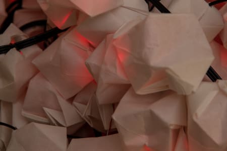 A close-up of decorative lights with geometric paper covers and red illumination