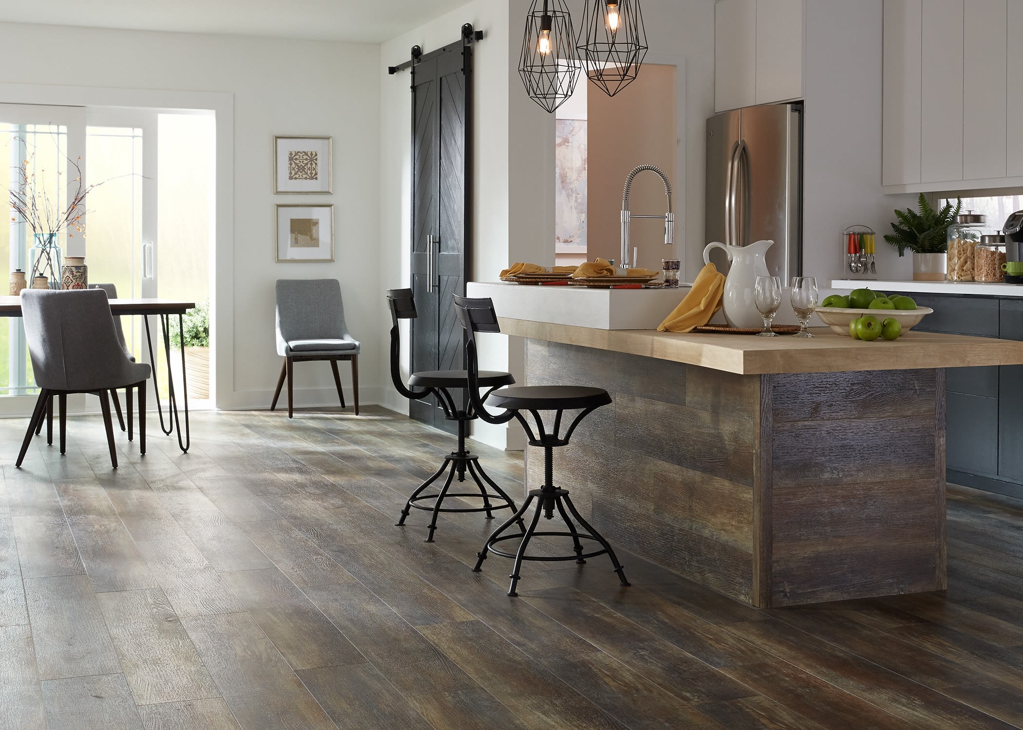 This inspiring kitchen features butcher block countertop, industrial pendant lights, and vinyl plank flooring as decor