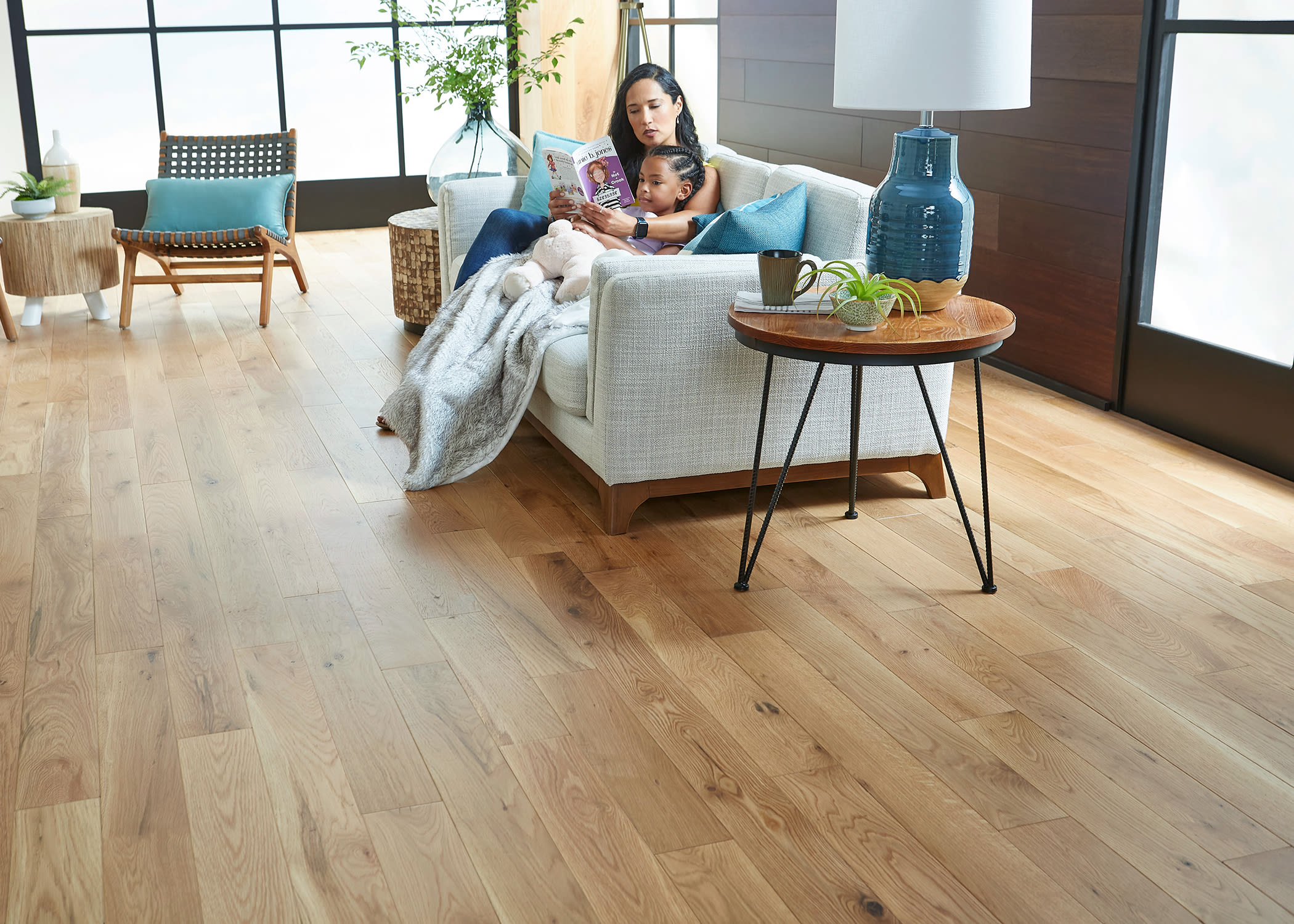 woman and child on sofa read a book in living room with hardwood flooring