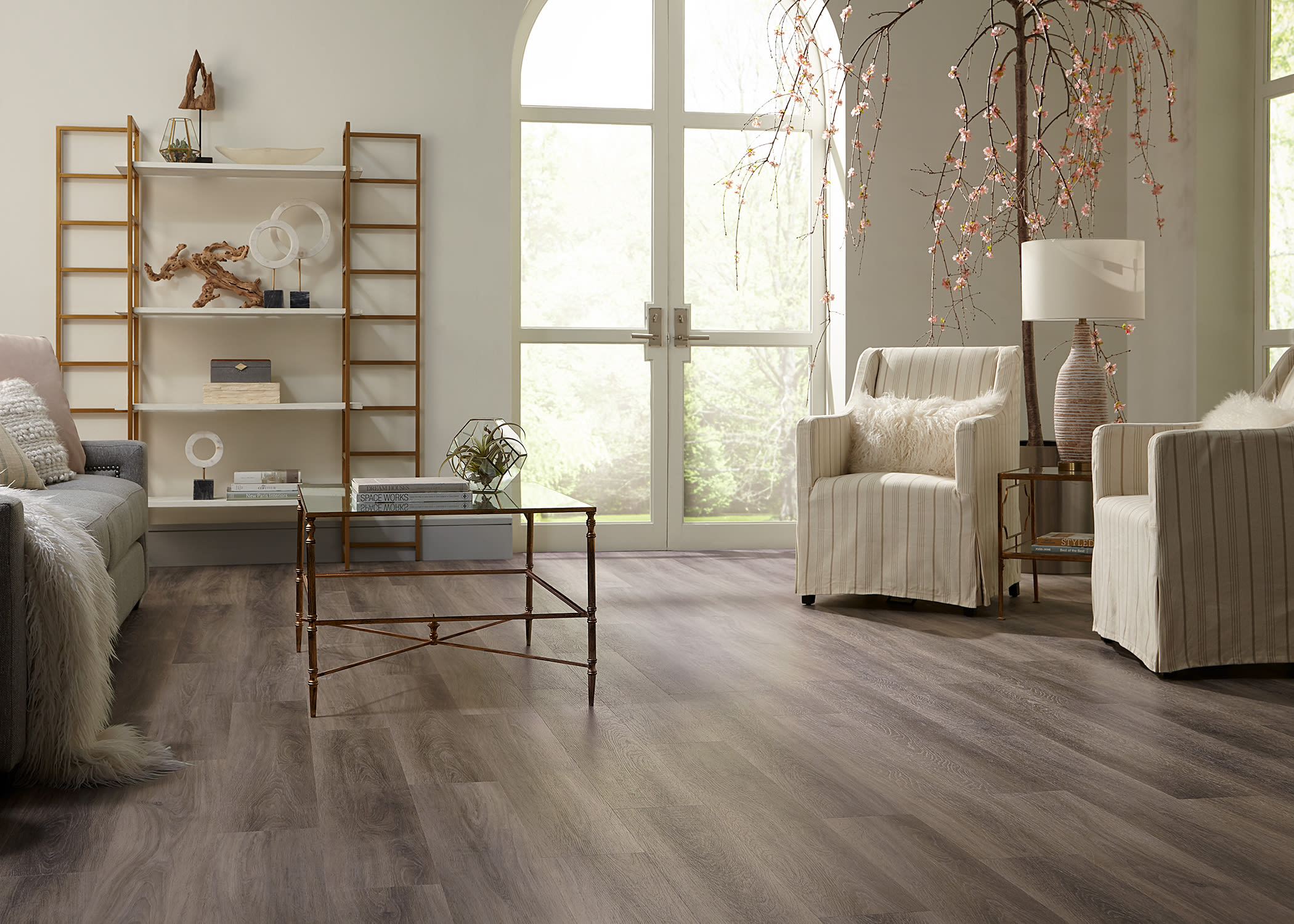 large room with wooden accents, blossoming tree feature, and rigid vinyl plank flooring