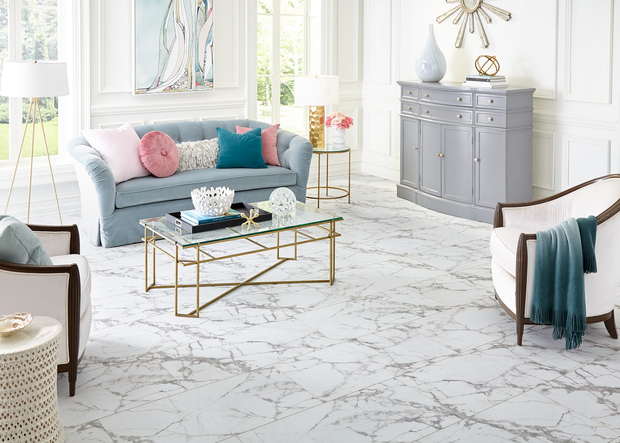 This fresh, bright living area combines a tufted sofa, wicker side table, wood and leather chairs, and the bright look of De Milo rigid vinyl plank flooring.