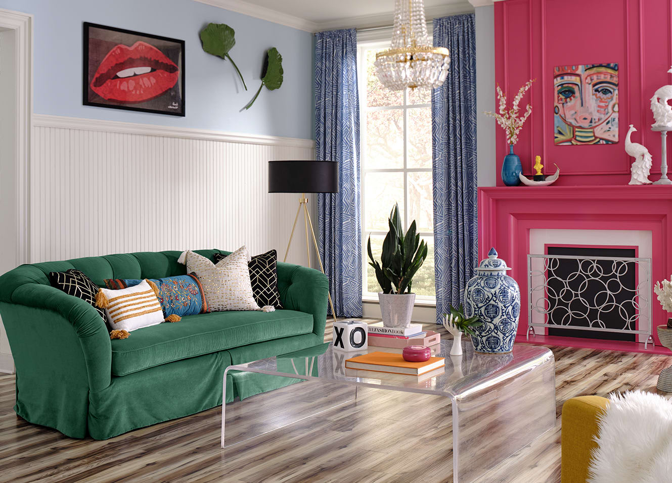 Living room of this home features rounded acrylic coffee table, pink sofa, and eclectic art. With Verona Myrtle Waterproof Rigid Vinyl Plank Flooring