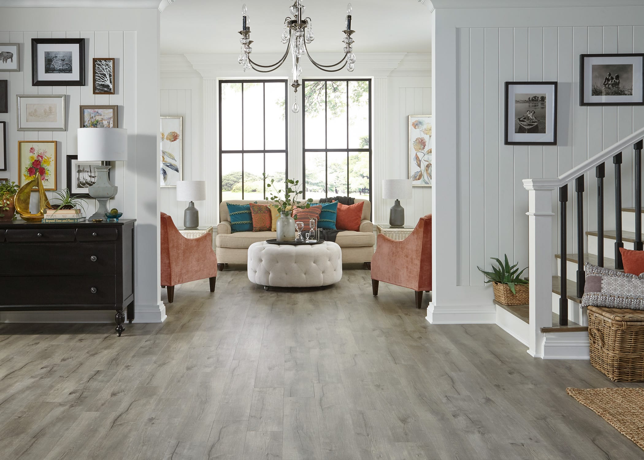 This view across entryway into a living room shows smart storage. To the left, a dresser used as a buffet, and a wicker basket adding more storage with style.