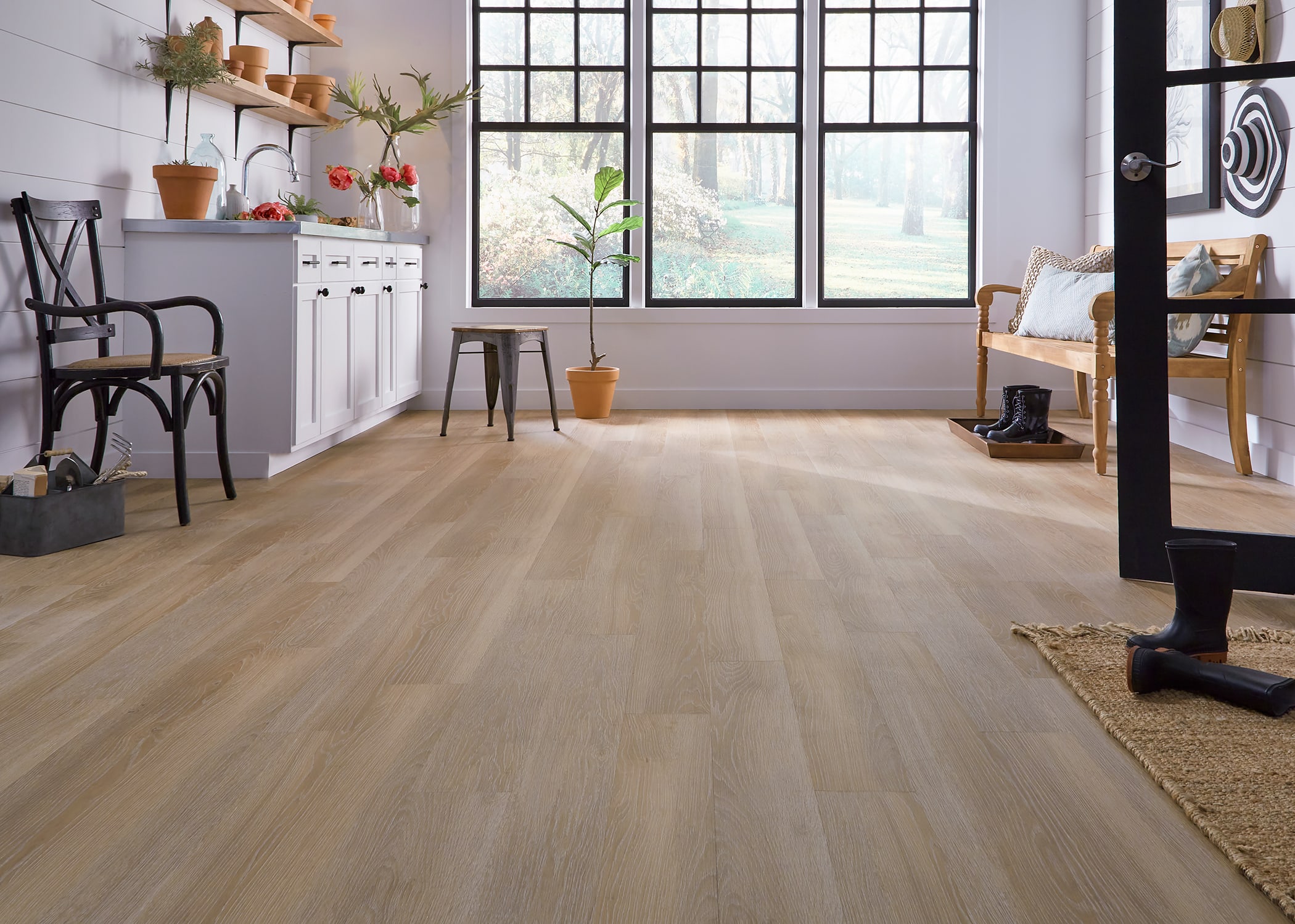 This mudroom uses wall hooks, a stylish bench, and waterproof vinyl plank flooring