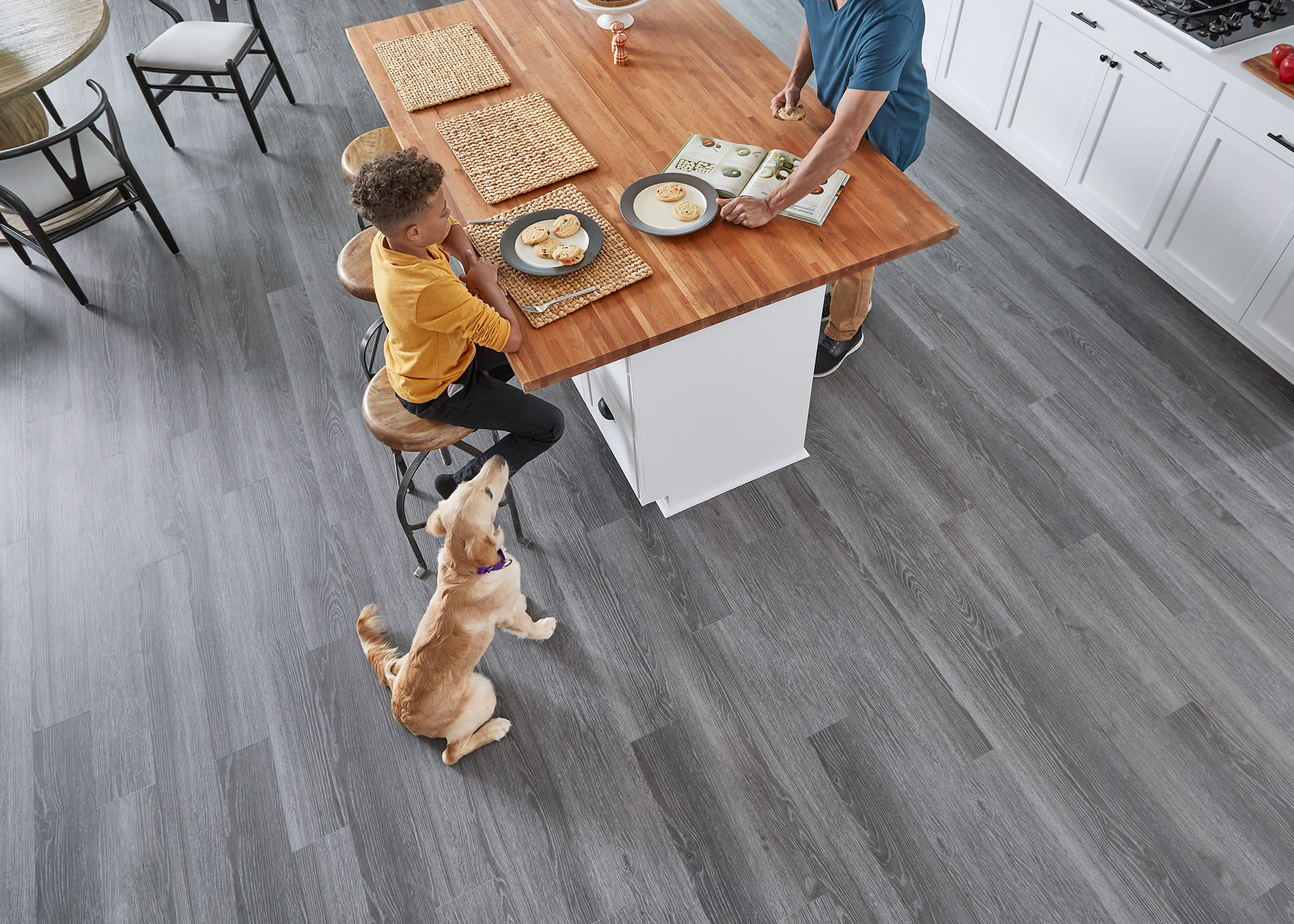 this kitchen shows gray wood look rigid vinyl plank flooring with a boy and dog