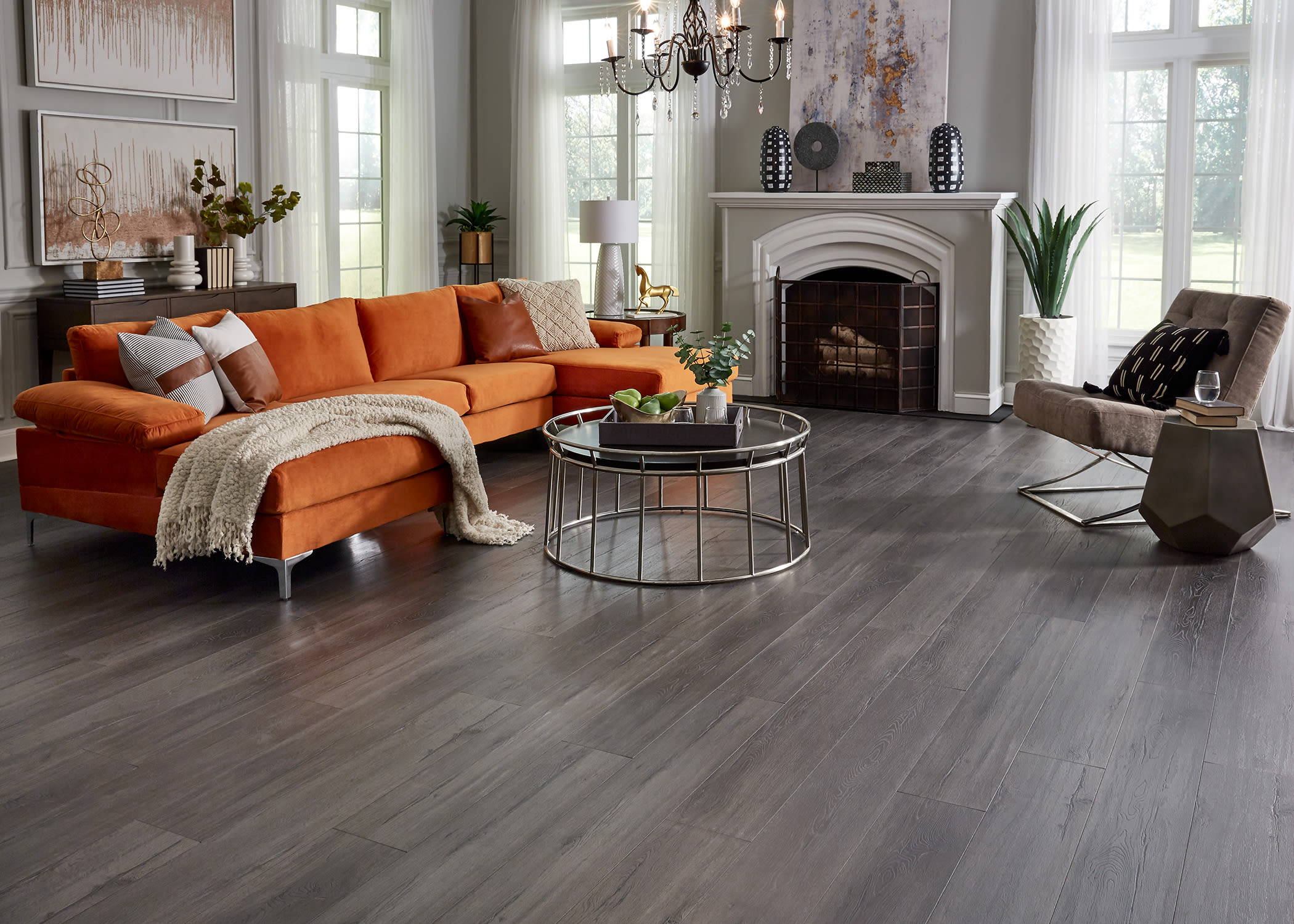 This gorgeous living room features comforting colors, orange sectional couch, and Duravana Waterproof Flooring from LL Flooring