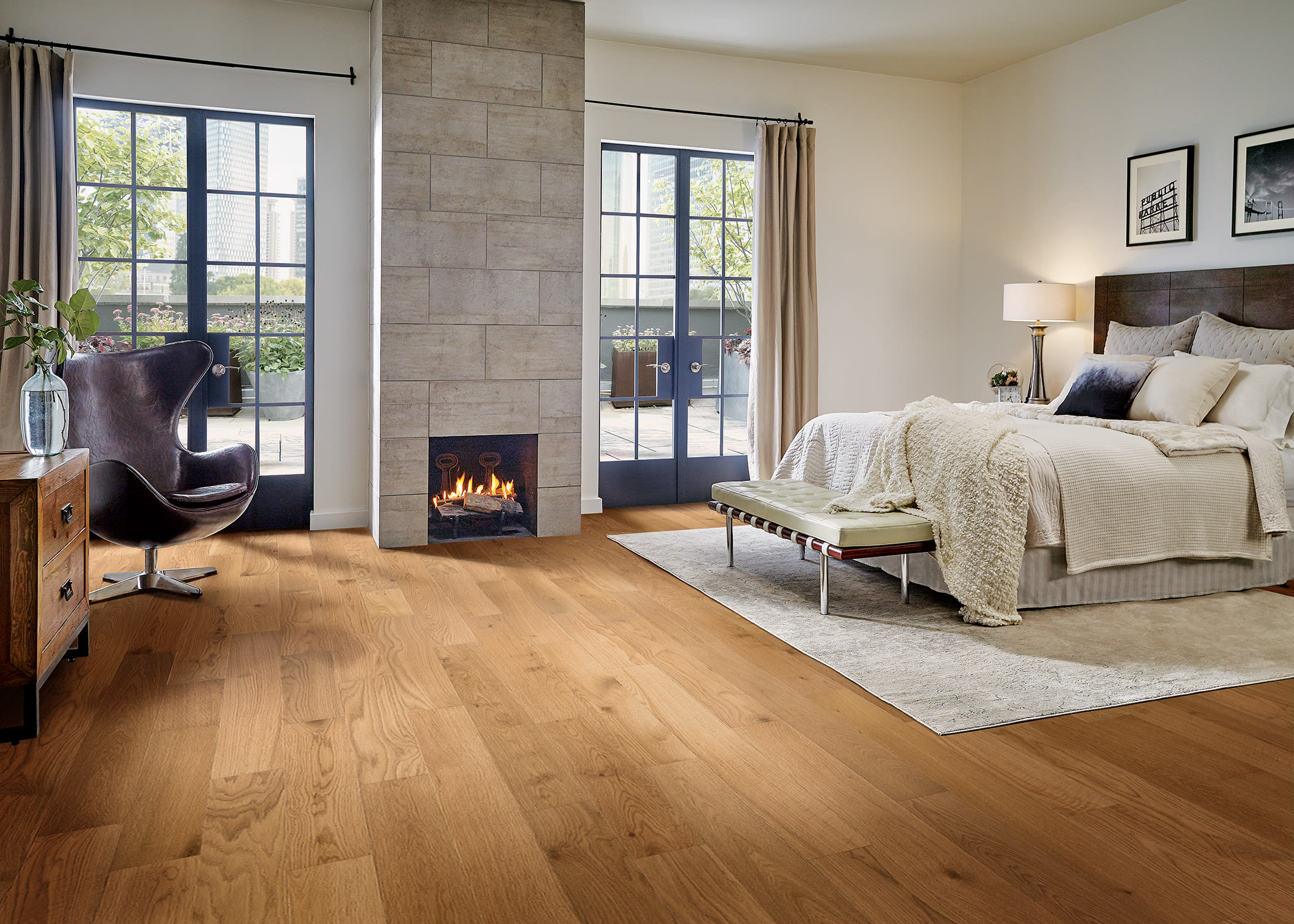 A fireplace crackles in this classy bedroom, designed with Gannett Peak White Oak engineered hardwood flooring.