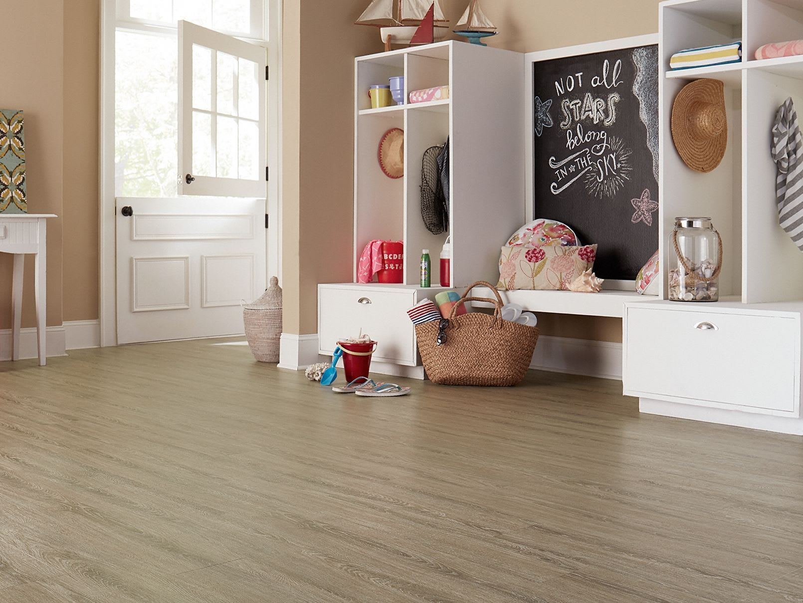 This entryroom is organized with white cabinets and waterproof floors