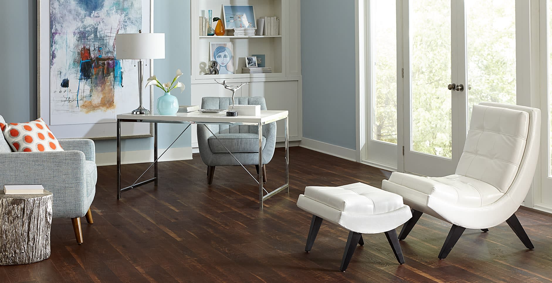 This living room/office uses simplicity and upbeat style for furniture choices, with curved leather chair and ottoman. With Old Dominion Walnut waterproof rigid vinyl plank.