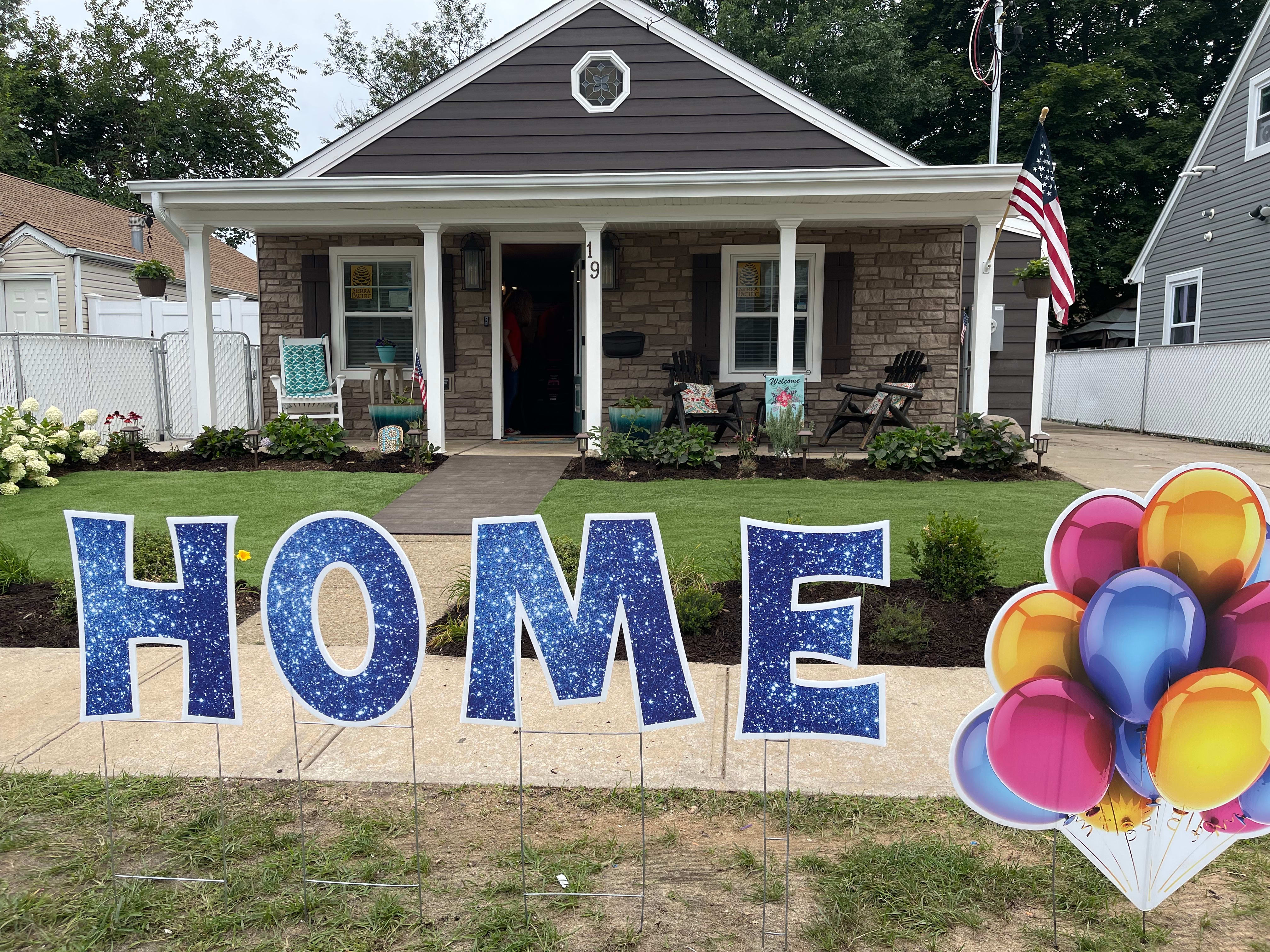 home with sign in lawn and colorful balloons